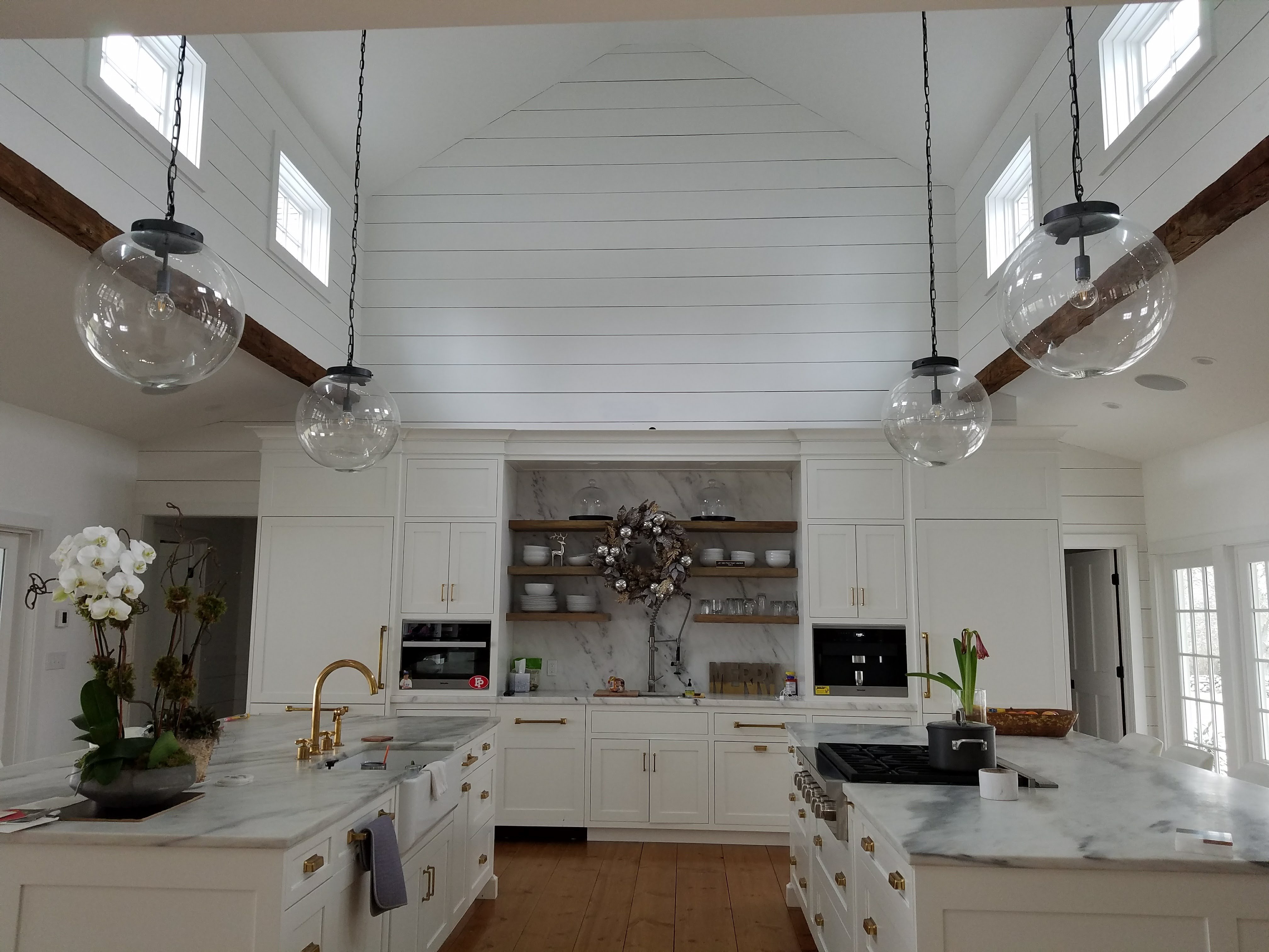 white walled kitchen with 4 light bulb light fixtures and dual islands