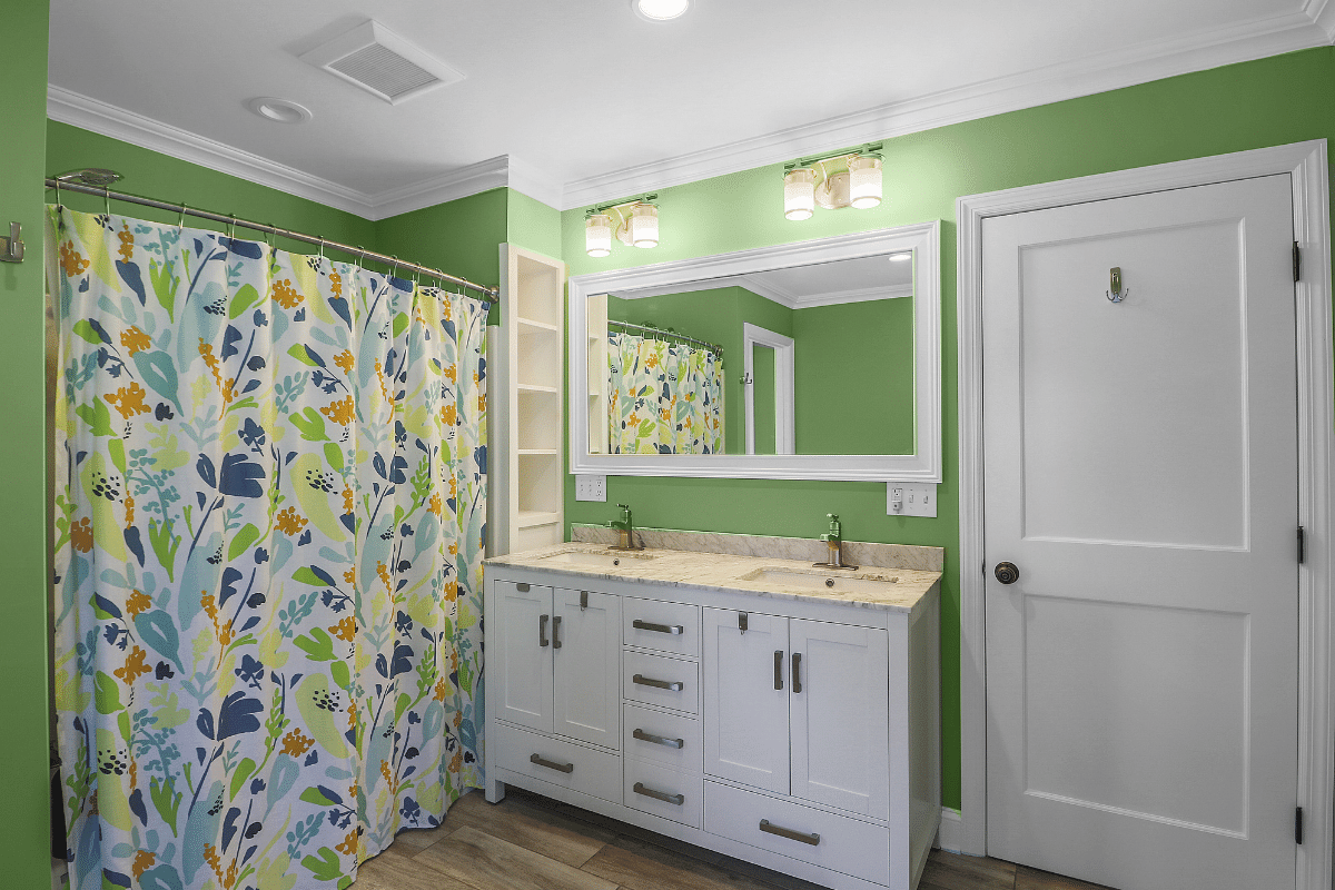 bathroom with green walls and white cabinets