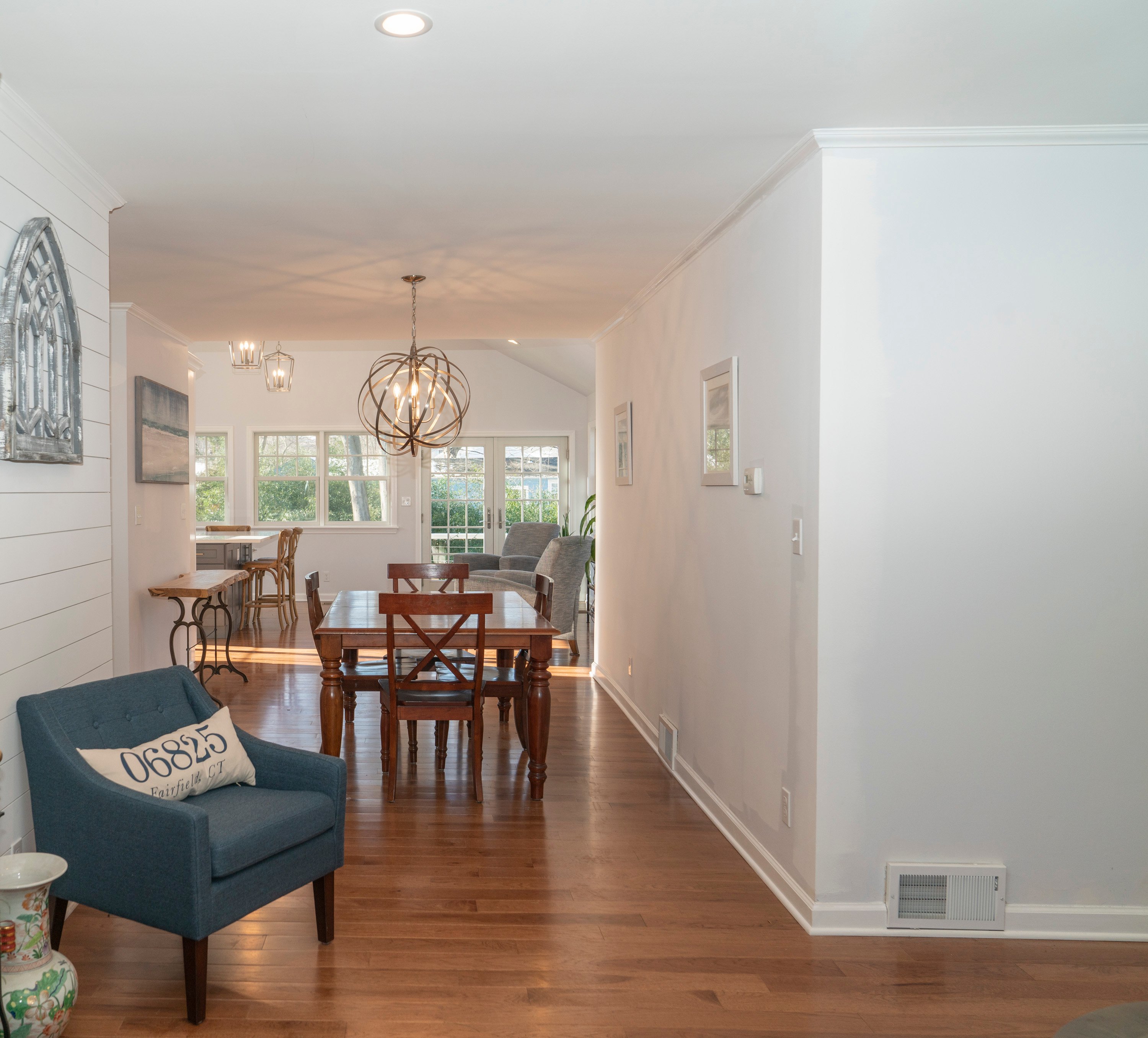 white seating area with round chandelier and brown flooring