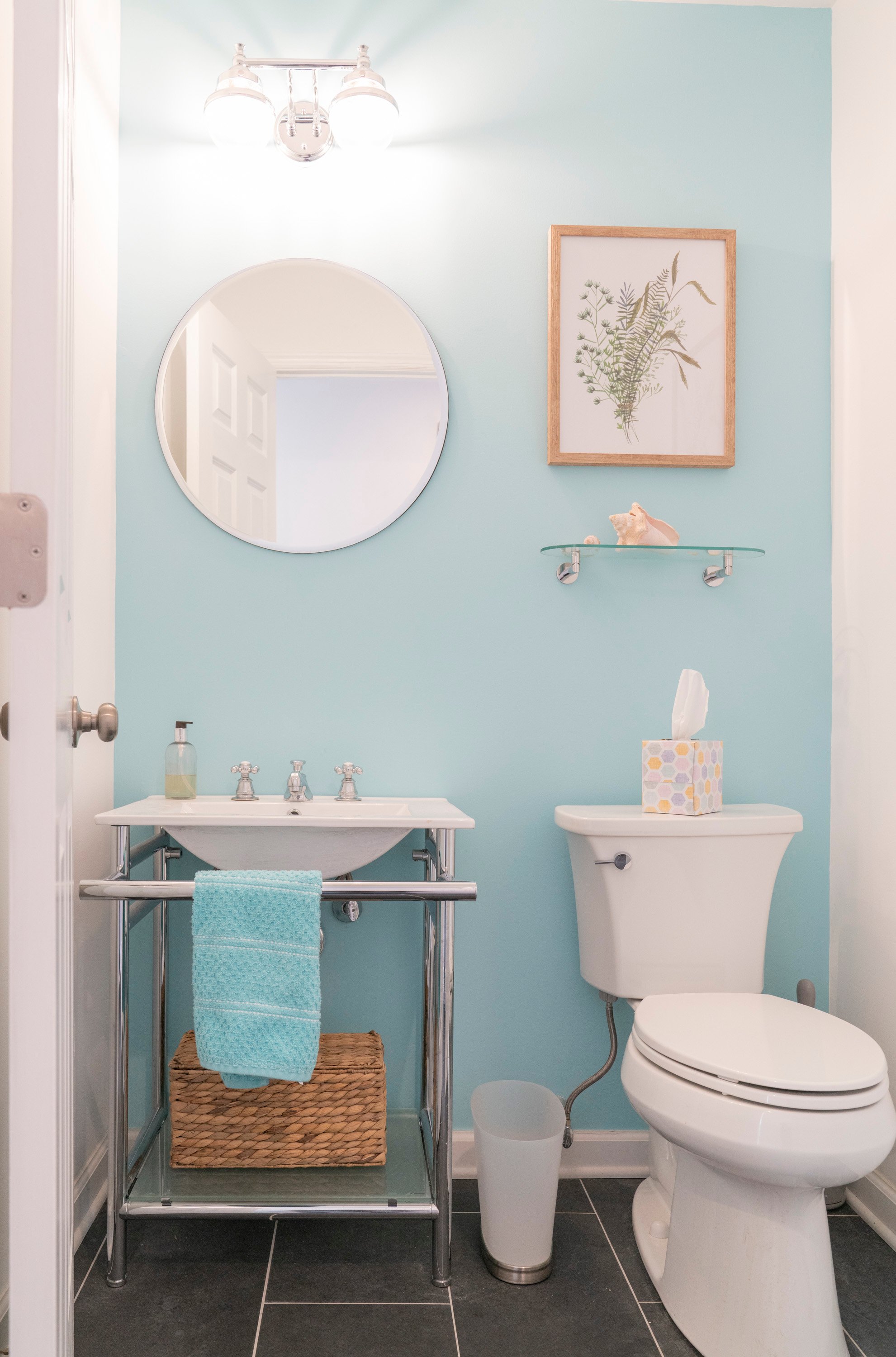 bathroom with blue walls and small round mirror