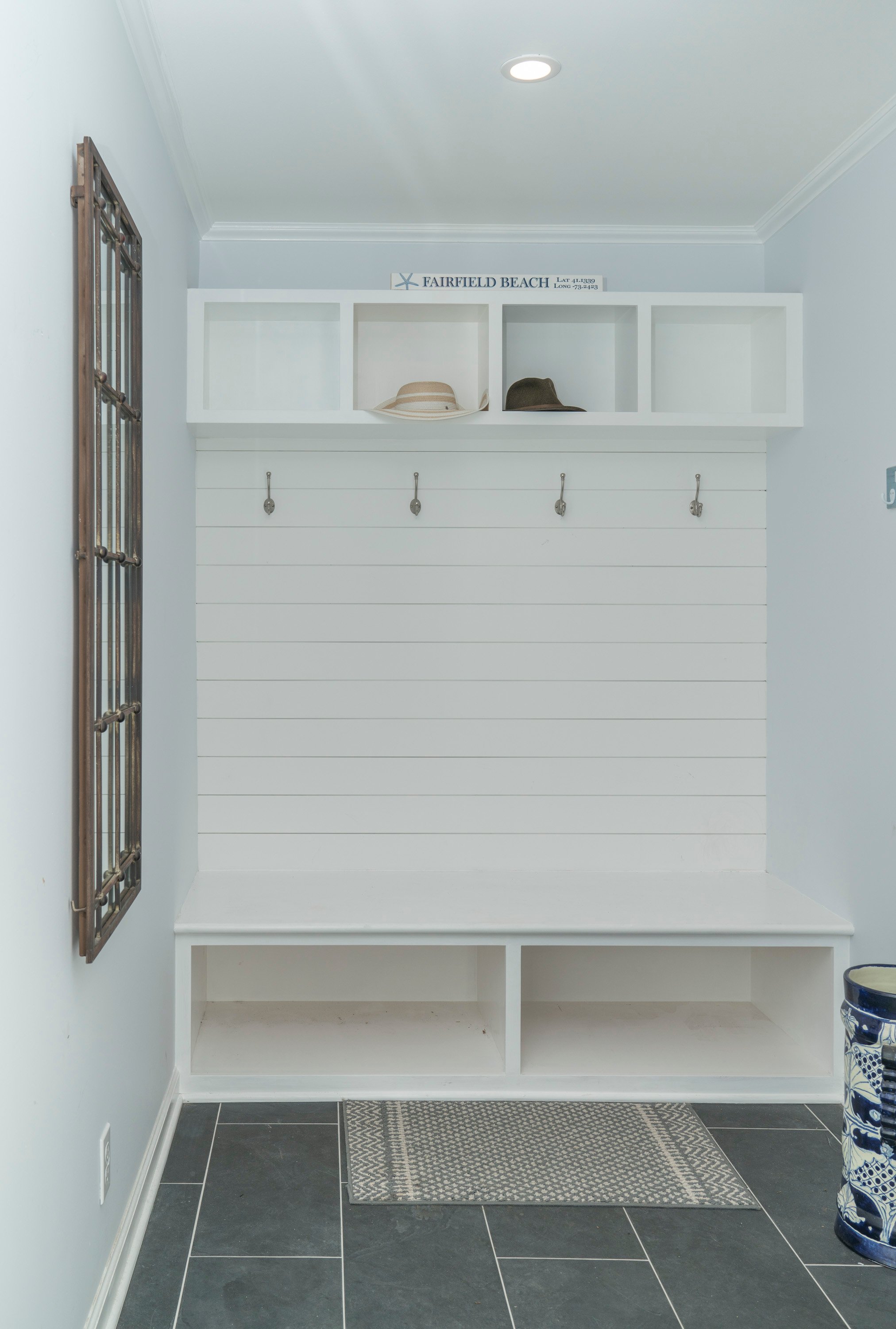 white mudroom with built in shelving and coat hangers