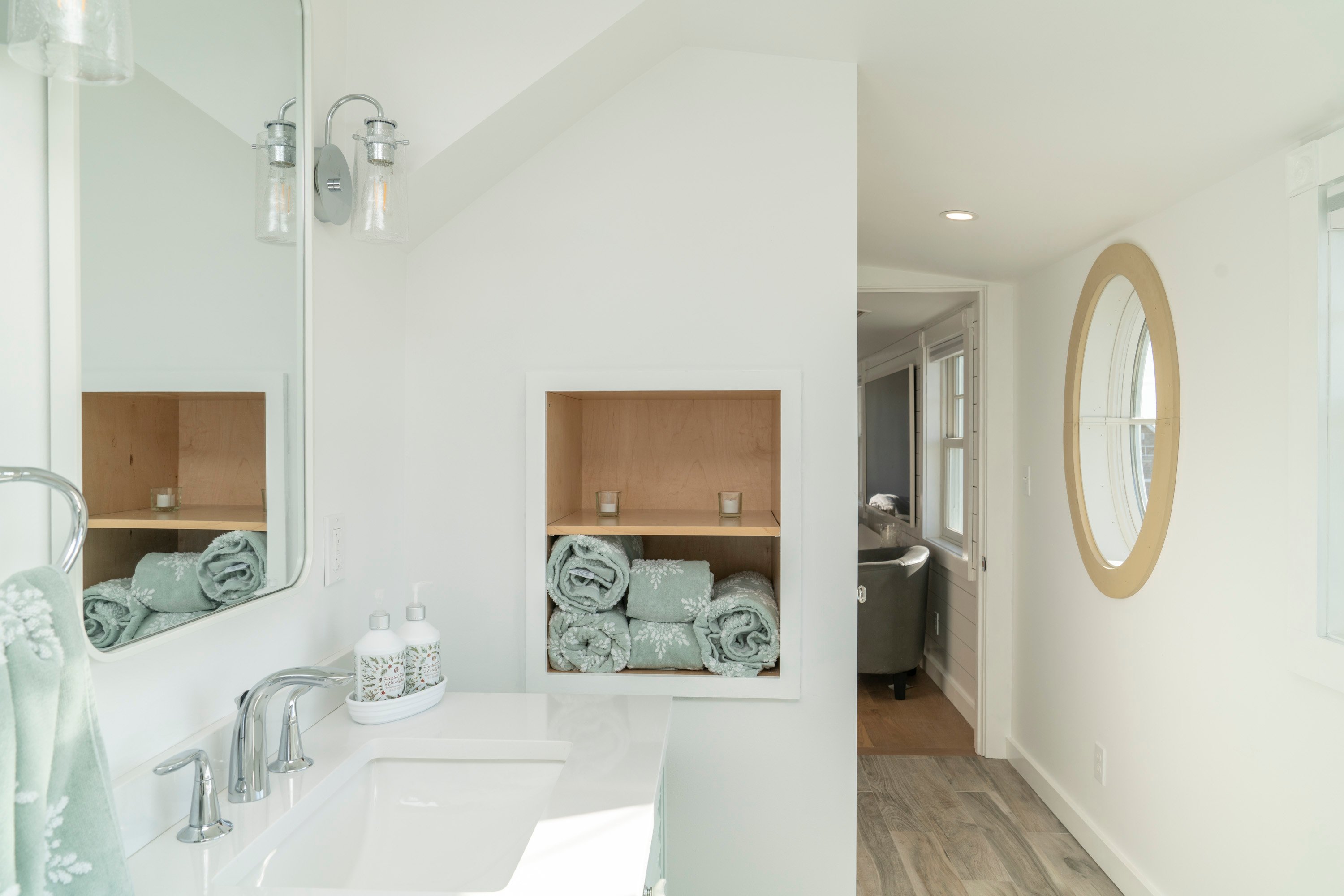bathroom with white walls and green towels with round window
