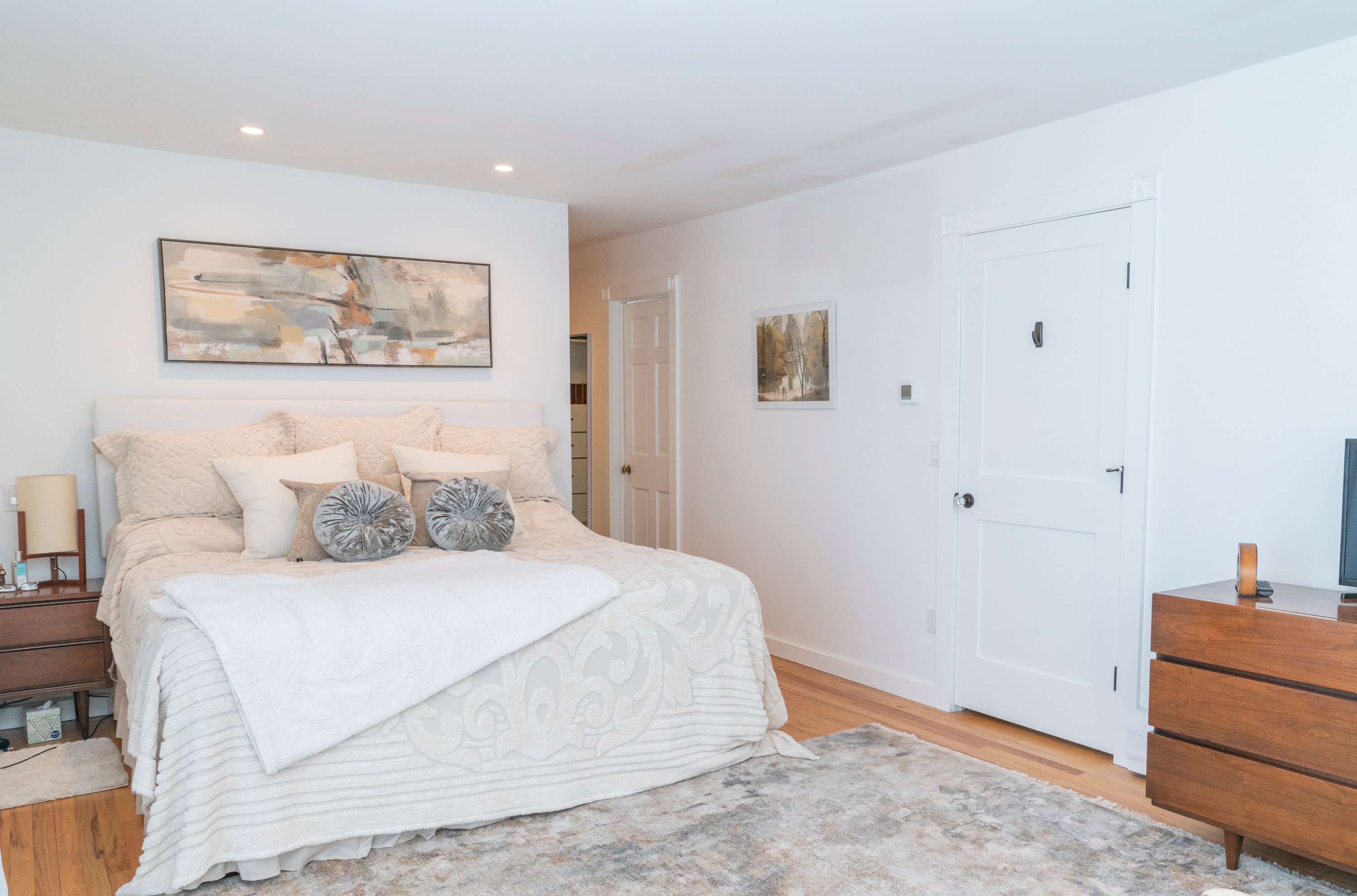 white bedroom with large bed and accent rug