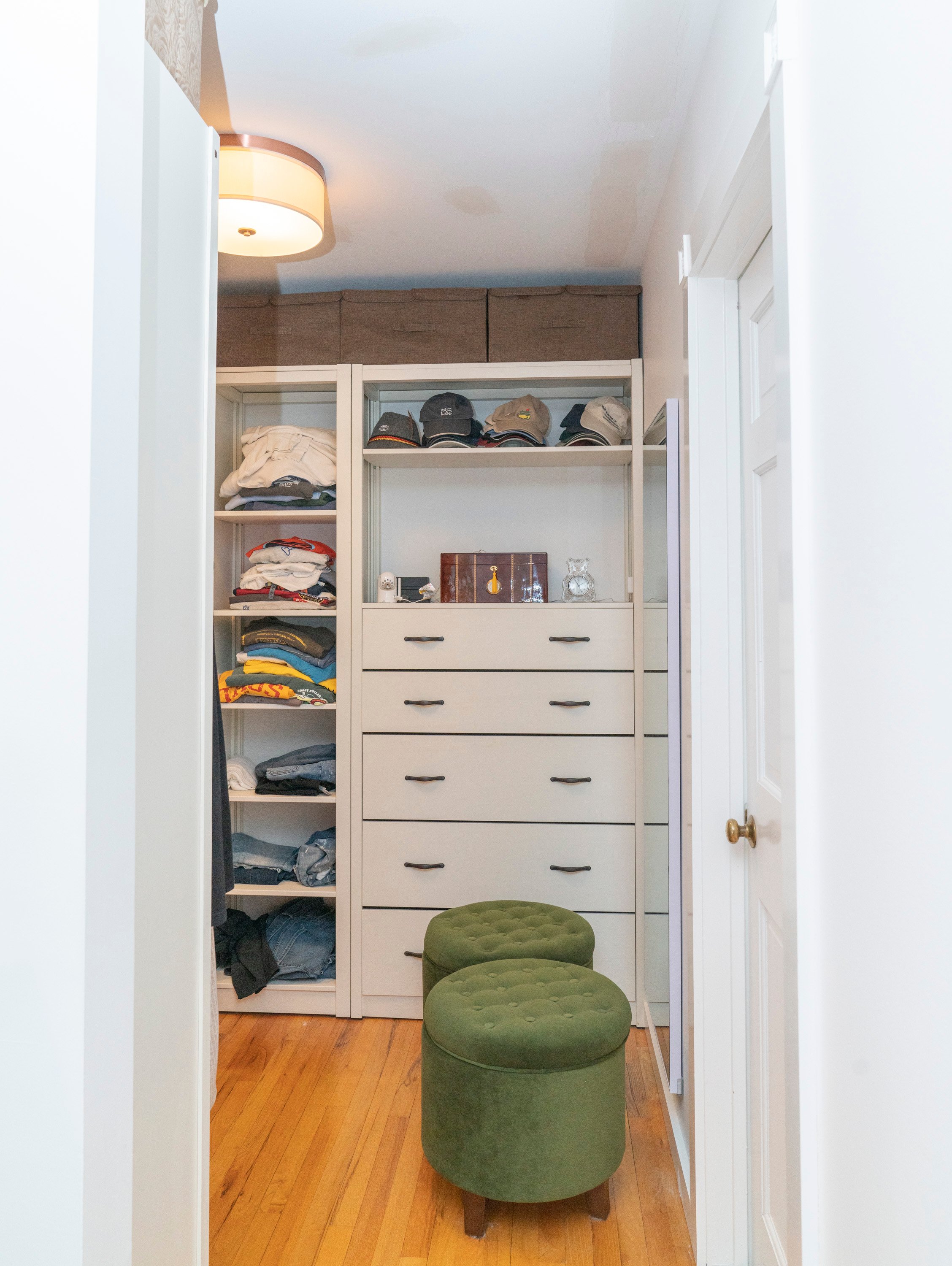 large walk in closet with built in shelving and green round chairs