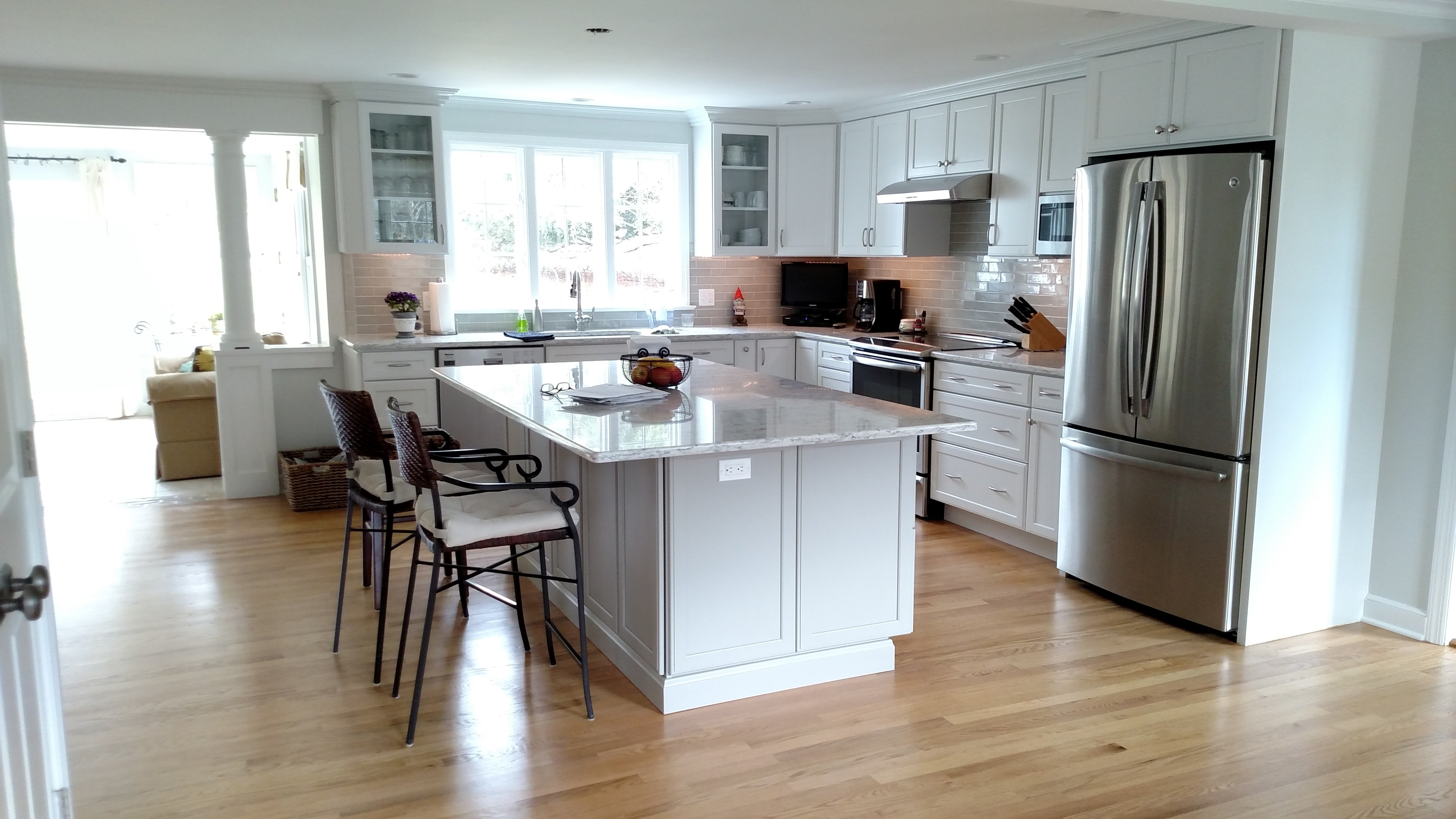 white kitchen with kitchen island and black bar stools