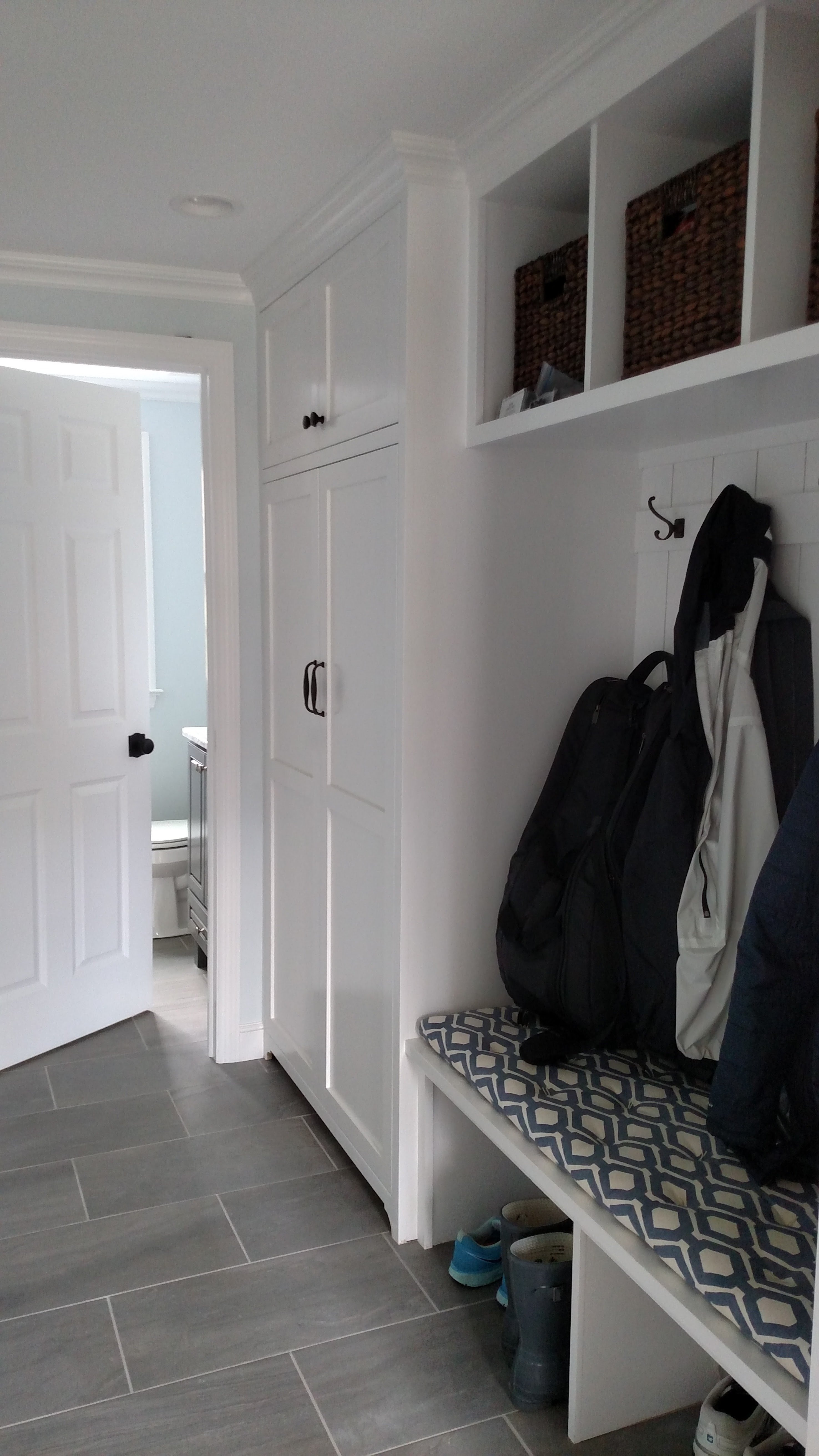 white mudroom with built in shelving and coat racks